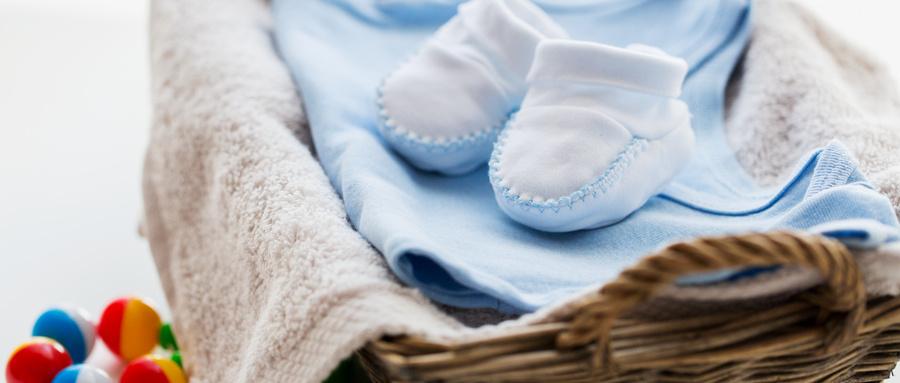 摄图网_300603078_服装,婴儿,母亲象白色婴儿靴与堆衣服,毛巾拨浪鼓为新生男孩篮子(仅交流学习使用).jpg